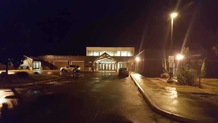 Contemporary institutional building photographed at night with parking area and exterior building illumination