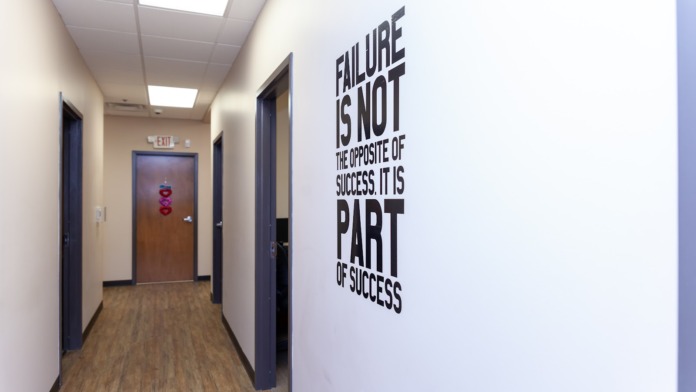 Interior hallway with white walls, dark doors, wood flooring, and motivational text wall decal about success