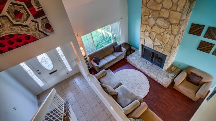 Interior overhead view of living areas with turquoise walls, stone fireplace, multiple seating zones, and windows.