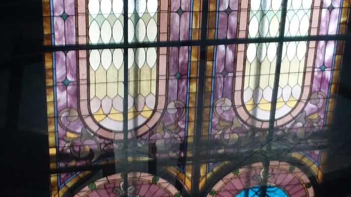 Interior decorative stained glass window with geometric patterns in multiple colors and ornate design elements.