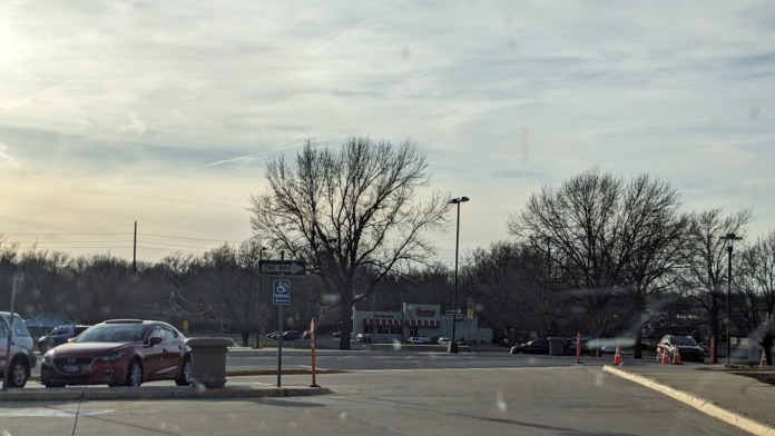 Exterior parking lot with landscaping, bare trees, street lighting, and facility buildings