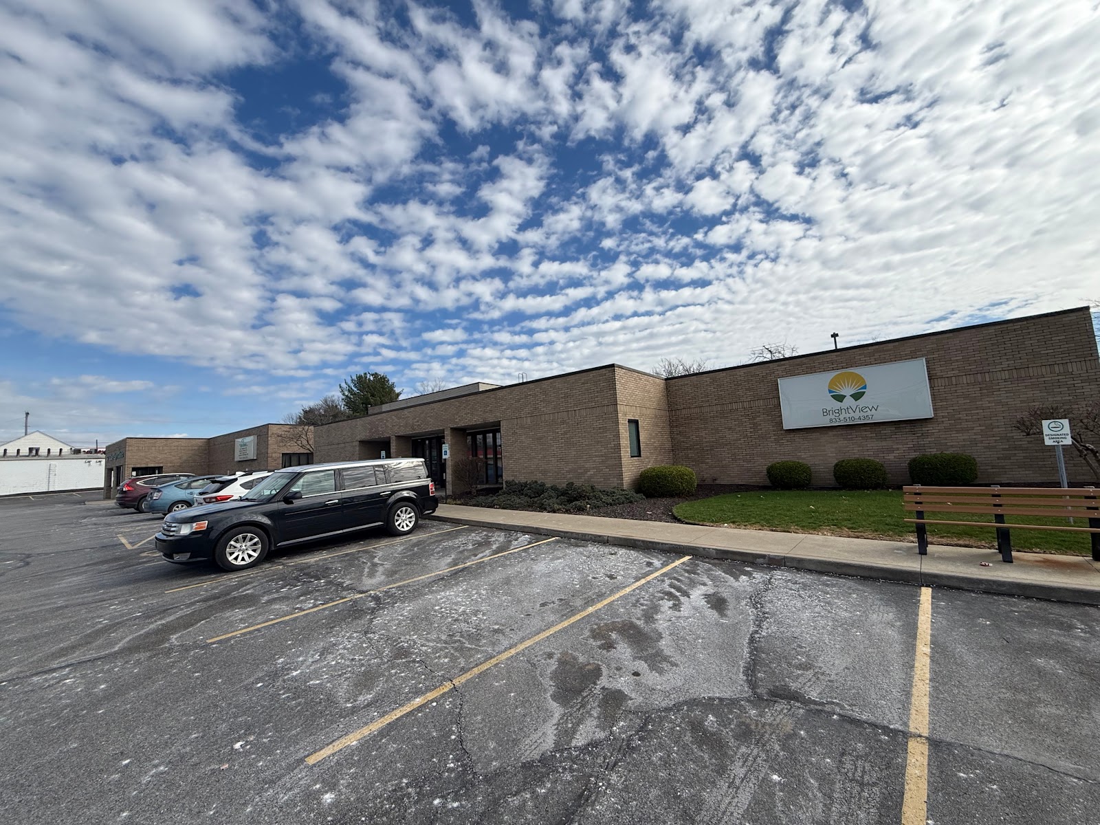 Wide angle exterior view showing parking lot, brick building facade, BrightView signage, and landscaping.