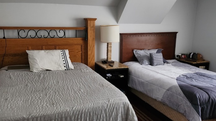Interior bedroom featuring two beds with wood and burgundy headboards, matching nightstands, and angled ceiling