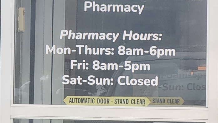 Exterior pharmacy entrance with Crossroads Health signage, pharmacy hours, automatic door notice, and facility policies.