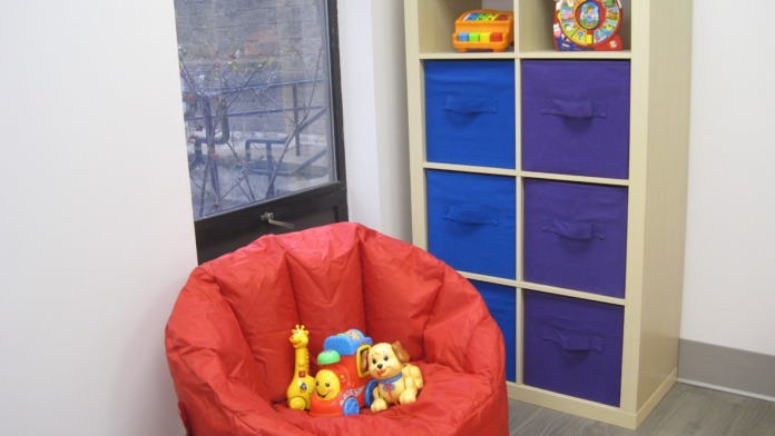 Interior space with red bean bag chair, storage unit with colored compartments, educational toys, and window