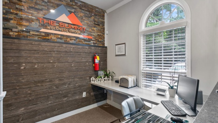 Interior reception desk with treatment center logo, stone accent wall, natural light, and check-in counter