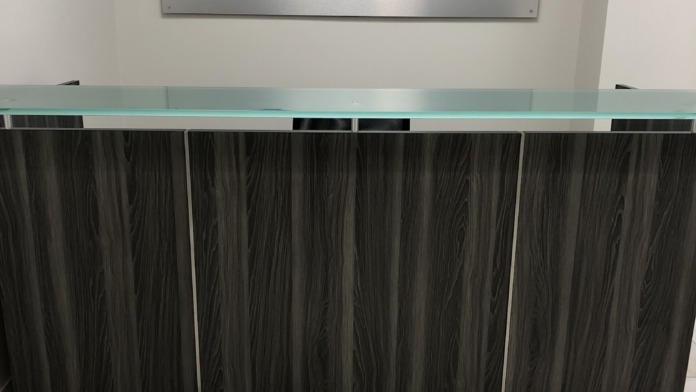 Interior reception desk displaying Arise Recovery Centers logo signage above dark wood counter with glass top