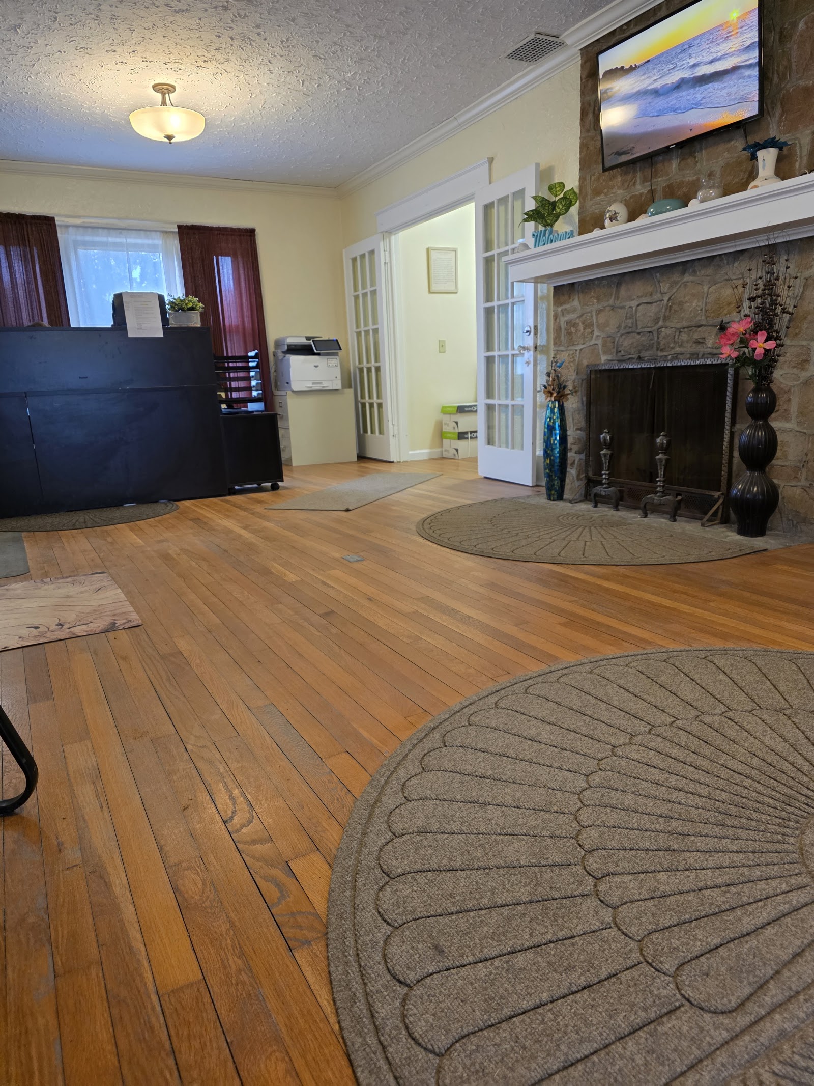 Interior reception lobby with stone fireplace, mounted television, wooden cabinetry, and seating areas