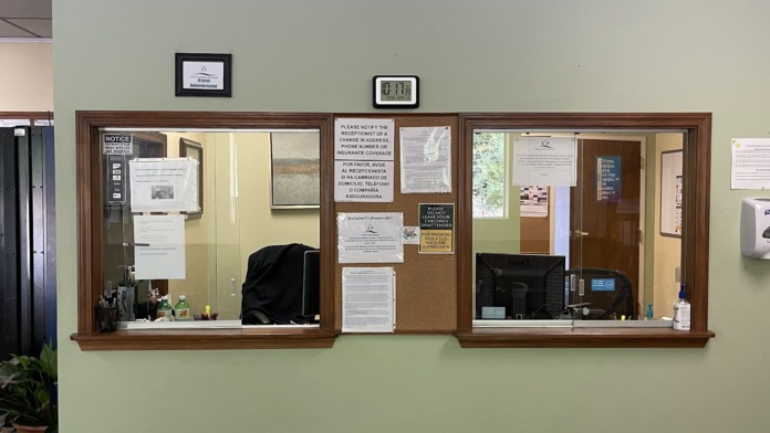 Interior showing reception desk with bulletin boards, documents, wall clock, green walls, and wooden door frames