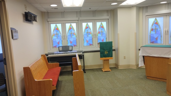 Interior chapel space with wooden pews, religious altar furnishings, and stained glass windows
