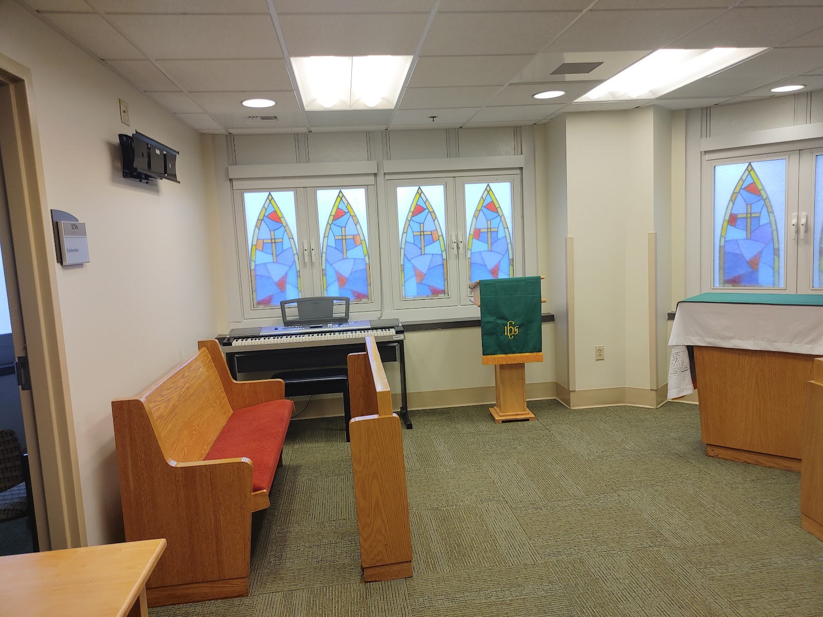 Interior chapel space with wooden pews, religious altar furnishings, and stained glass windows