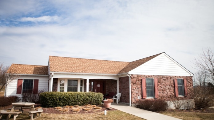 Single-story brick building with covered front porch, concrete walkway, and professional landscaping.