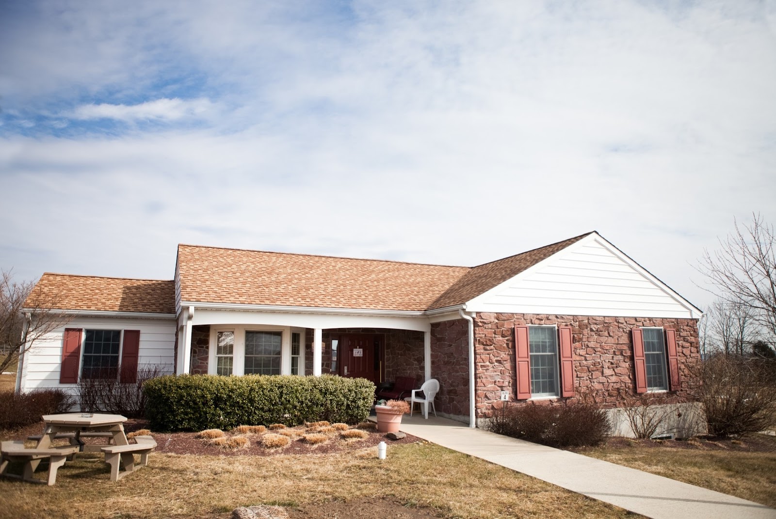 Single-story brick building with covered front porch, concrete walkway, and professional landscaping.