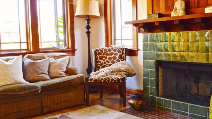 Interior living room with leather sofa, patterned chair, fireplace with green tile, and natural wood trim