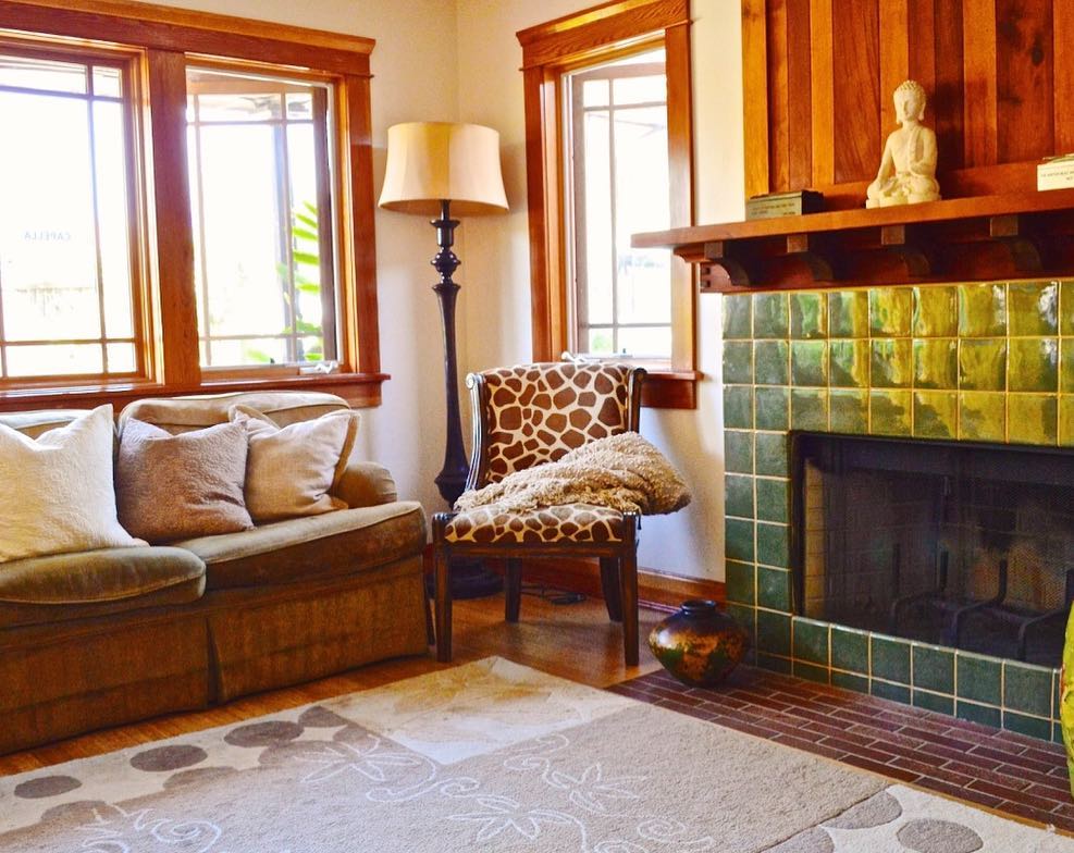 Interior living room with leather sofa, patterned chair, fireplace with green tile, and natural wood trim