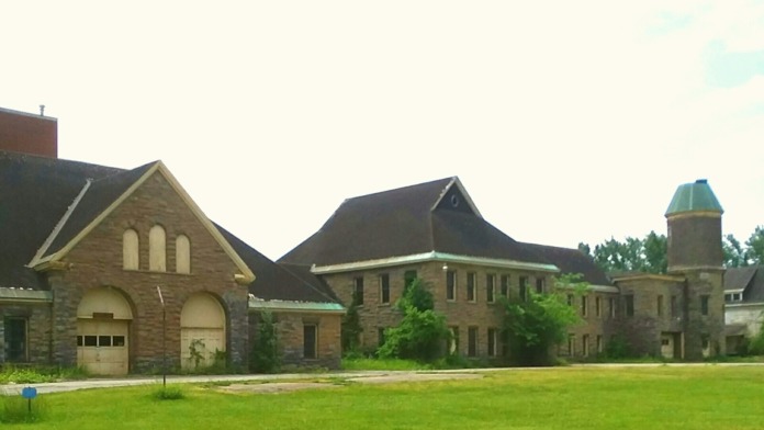 Exterior view of stone institutional buildings including chapel with arched windows and separate tower structure