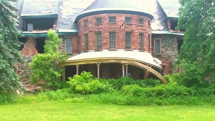 Exterior Victorian-style building with curved portico, turret, and ivy-covered stone walls on landscaped grounds