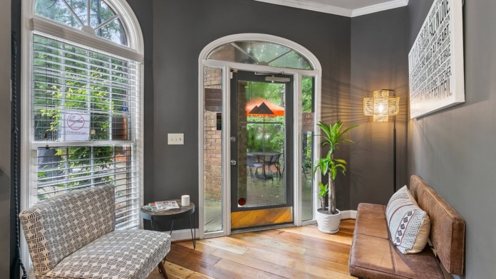 Interior waiting area with comfortable seating, doors to outdoor patio, large windows, plant accents, and professional decor