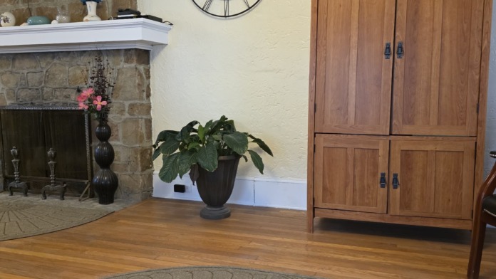 Interior waiting room with stone fireplace, TV on mantel, wooden cabinetry, decorative clock, and patterned rug