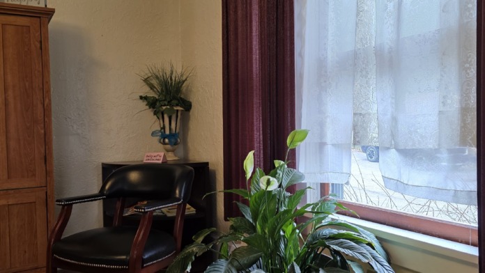 Interior reception area with seating chairs, coat rack, and doorways leading to facility common spaces