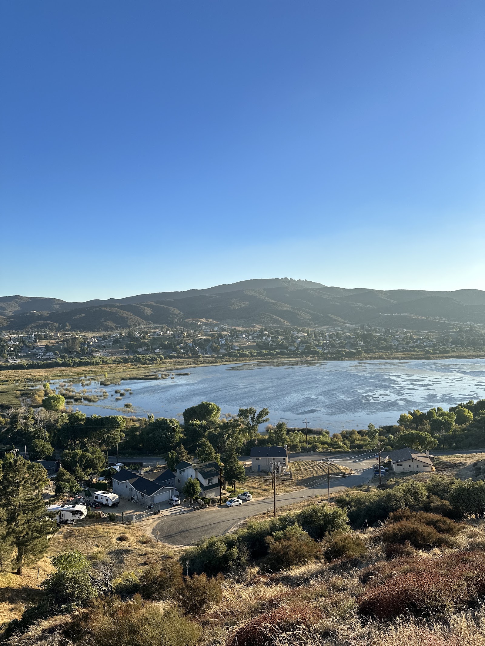 Aerial view of rural facility property with buildings, water features, vegetation and distant mountain range