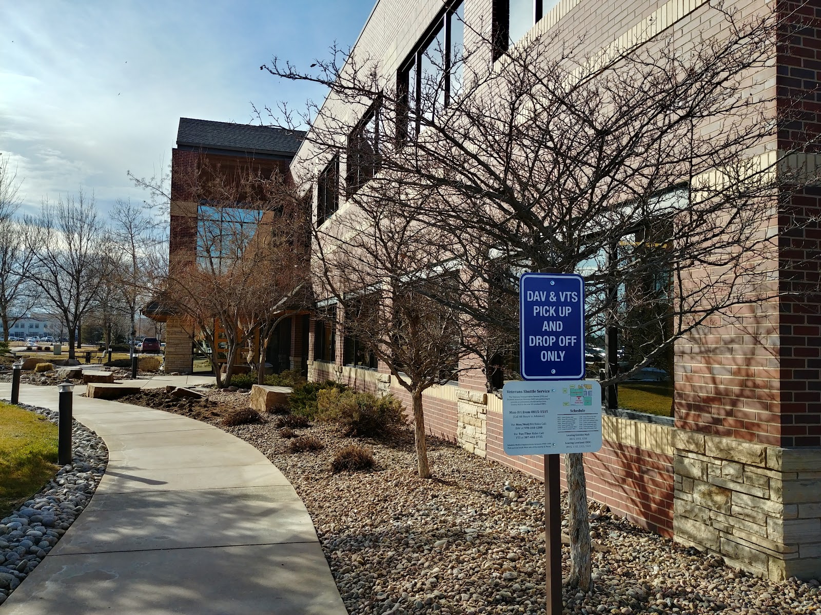 Exterior view showing brick building, covered entry walkway, bare trees, and DAV drop-off signage