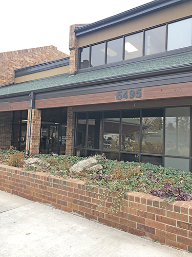 Exterior view of brick treatment facility building with large windows, landscaped planter beds, and storefront entrance