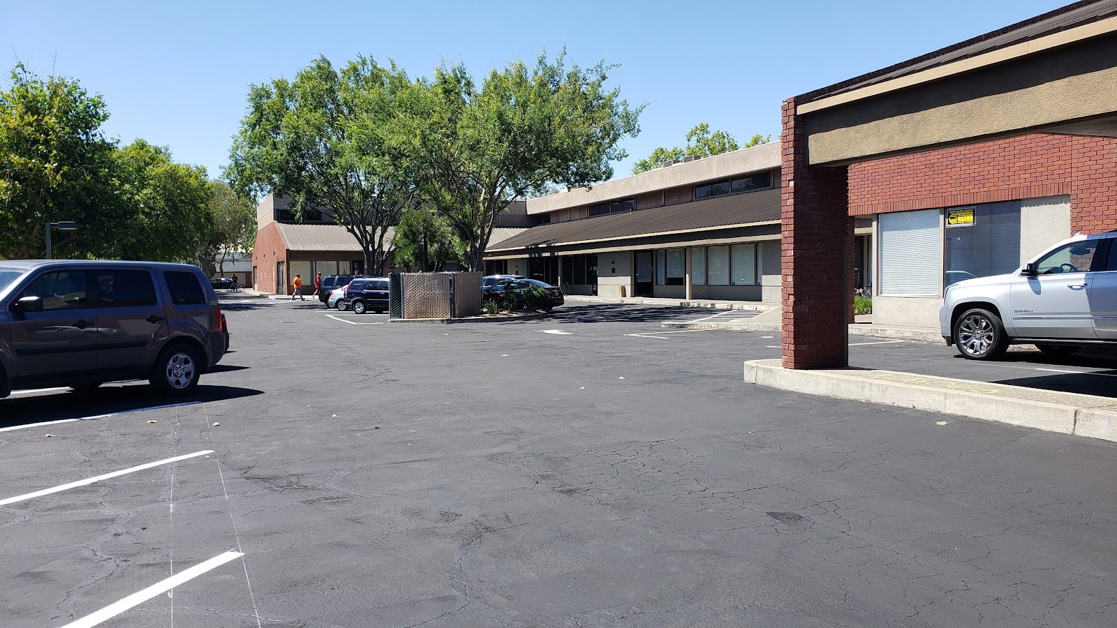 Exterior view of brick and stone treatment facility building with parking lot, landscaped trees, and clear sky