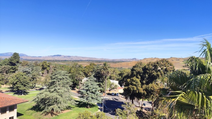 Exterior aerial view of medical facility campus with buildings, landscaping, and surrounding hills.