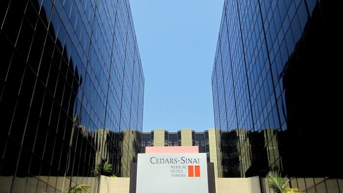 Exterior view of modern glass and steel medical office building with Cedars-Sinai Medical Office Towers signage and landscaping