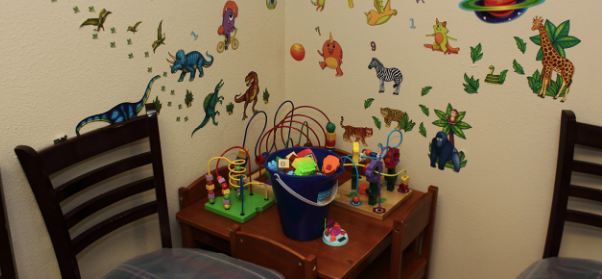 Interior play area with colorful animal wall decals, table with toys and play equipment, seating for children