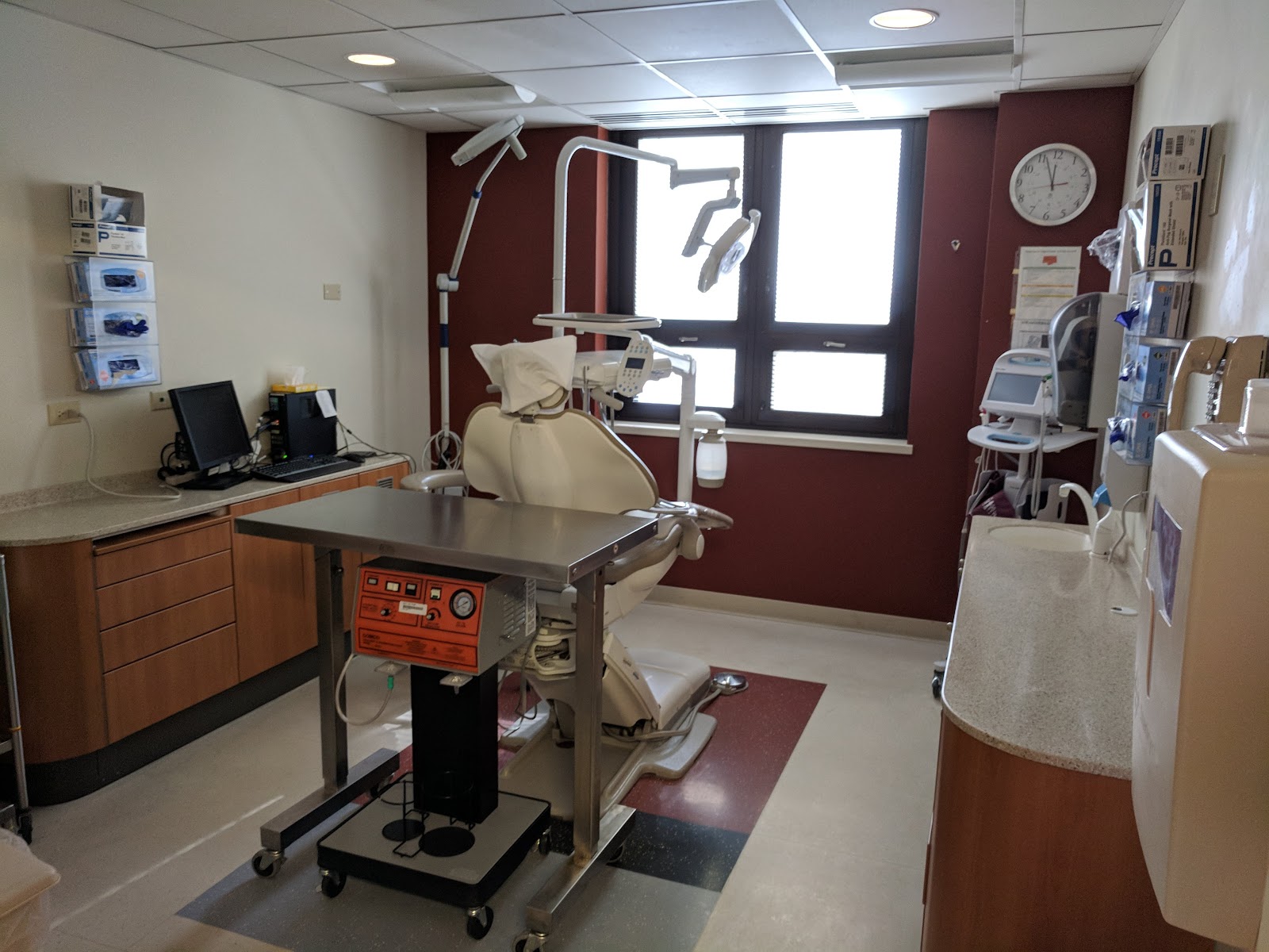 Interior clinical room with diagnostic exam equipment, overhead lights, computer workstations, and medical instrumentation