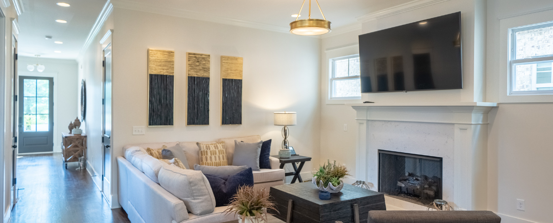 Interior living room with cream sofa, fireplace, television, artwork, and natural lighting from windows