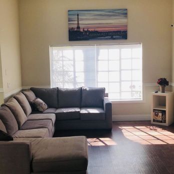 Interior common room with gray sectional sofa, window with natural light, and entertainment area