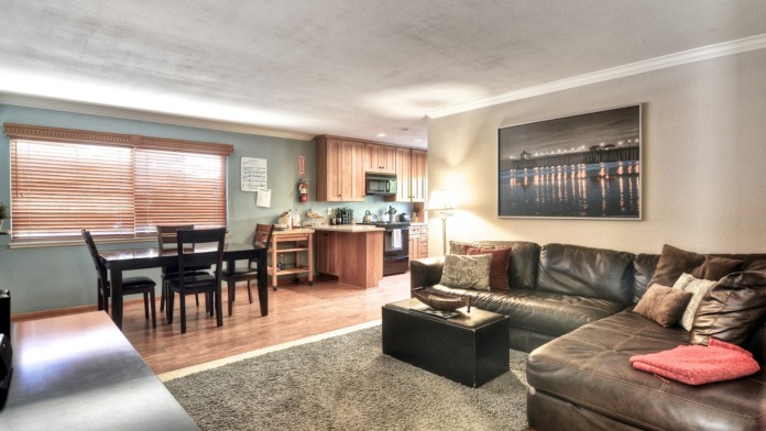 Interior community space with leather seating, dining table, kitchen area, and modern furnishings