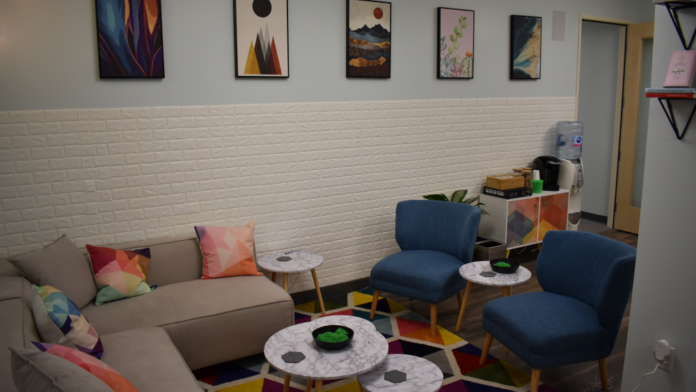 Interior lounge area with white brick walls, colorful rug, blue and beige seating, framed artwork, and modern furnishings.