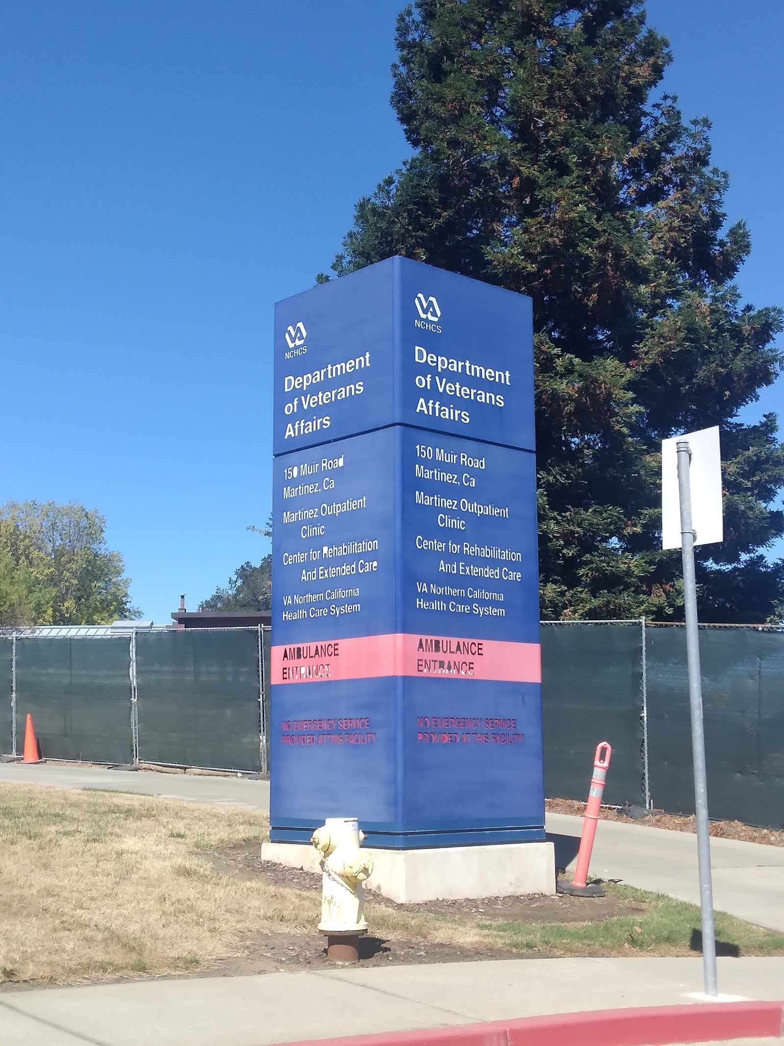 Exterior view showing VA facility directional sign with ambulance entrance marking and surrounding parking area