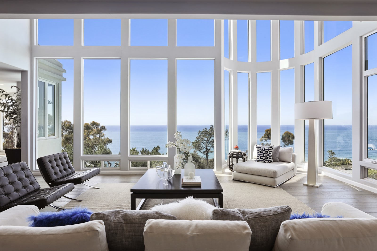 Outdoor elevated pool with turquoise water, wooden deck, seating furniture, and panoramic sunset ocean views