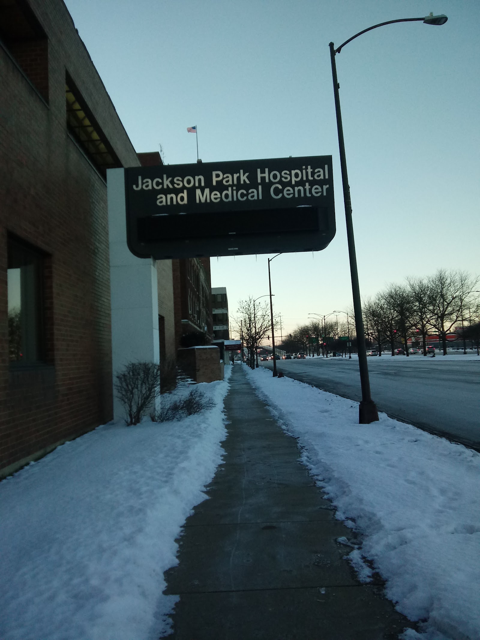 Exterior facility sign reading Jackson Park Hospital and Medical Center mounted on brick building with snow-covered ground visible