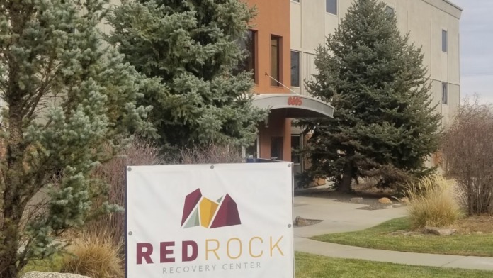 Exterior facility sign with Red Rock Recovery Center logo on landscaped grounds in front of building