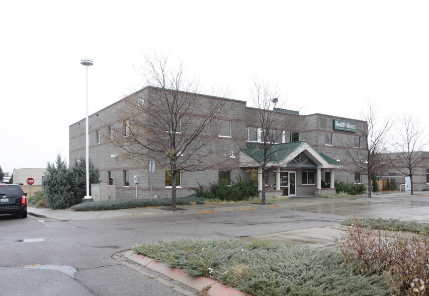 Exterior view showing full building structure with brick construction, parking area, bare landscaping, and street access