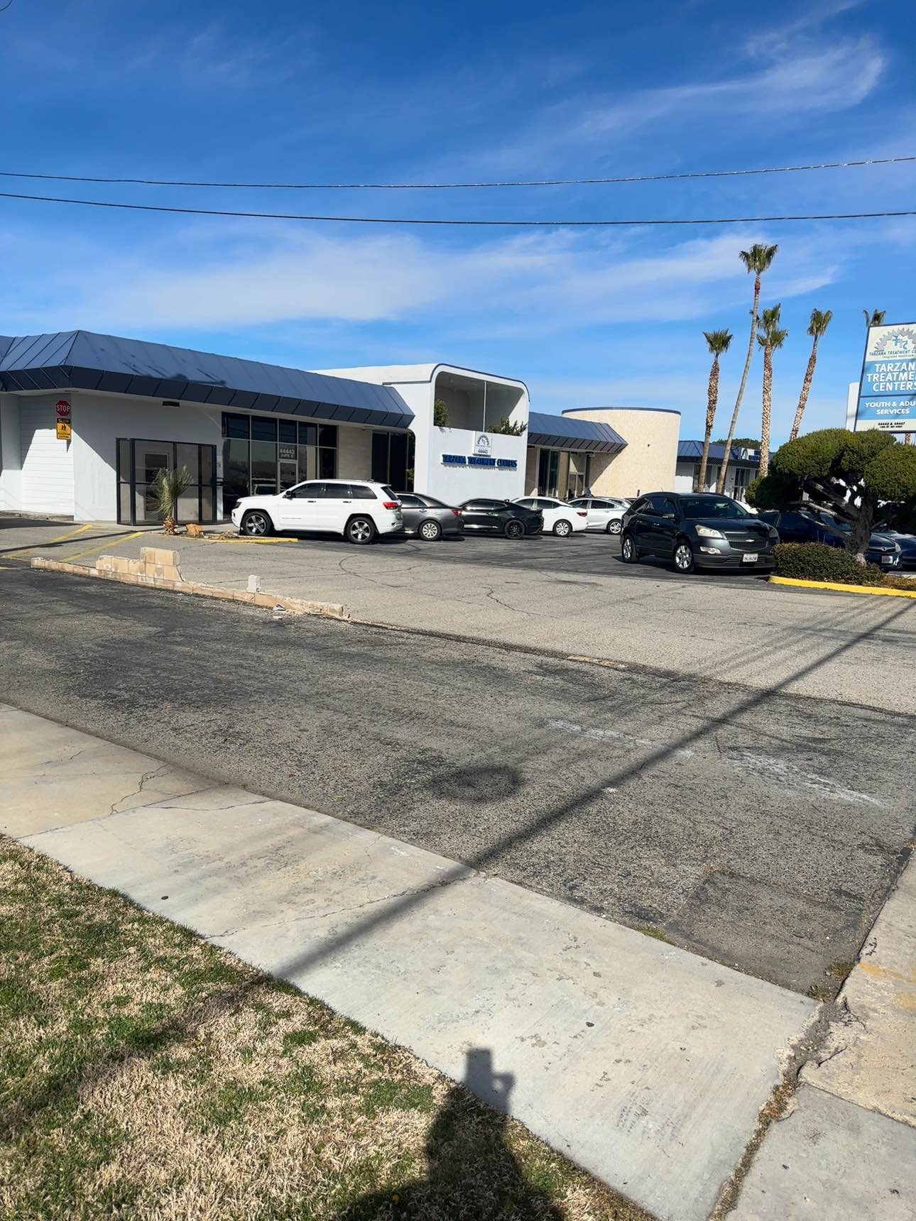 Exterior front showing modular building structures with terracotta roof, parking lot with multiple vehicles, and landscaping