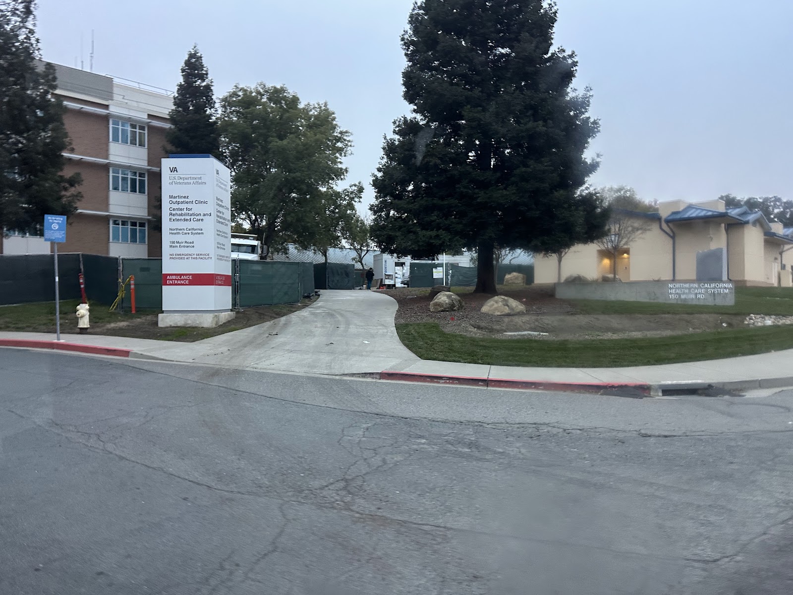 Exterior view of VA facility grounds showing building complex, landscaping, trees, and access roads