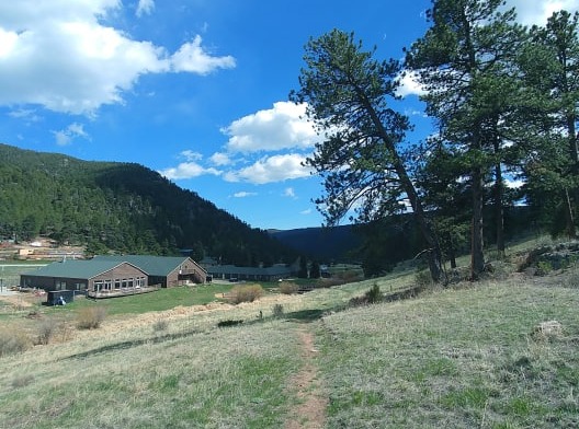 Exterior view of Fire Mountain Programs facility nestled in mountain landscape with buildings, grounds, and surrounding forested hills
