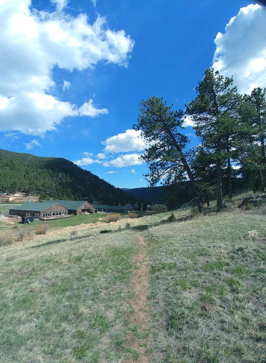 Exterior view of Fire Mountain Programs facility nestled in mountain landscape with buildings, grounds, and surrounding forested hills