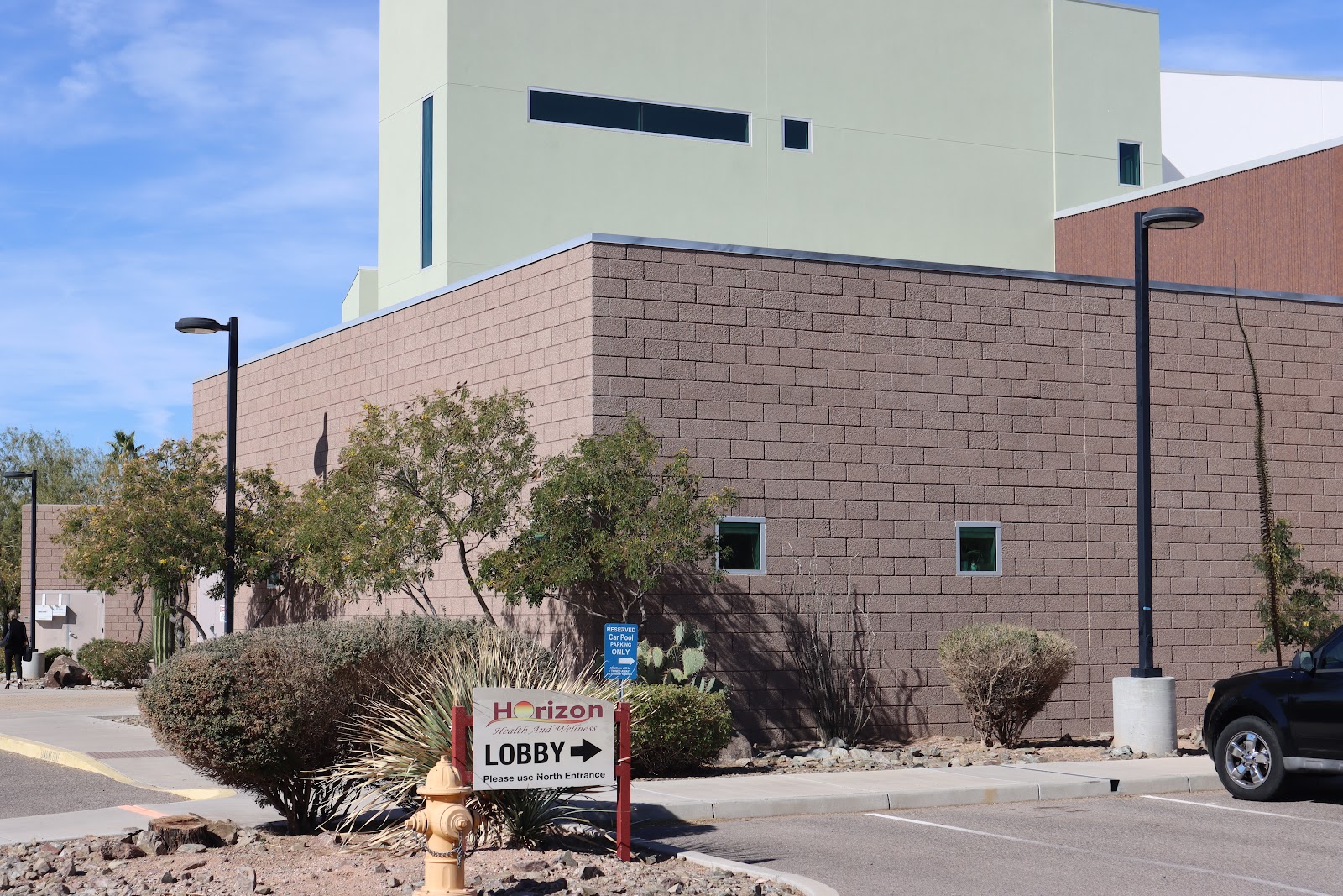 Exterior entrance to facility showing brick and white exterior, lobby signage, and parking area