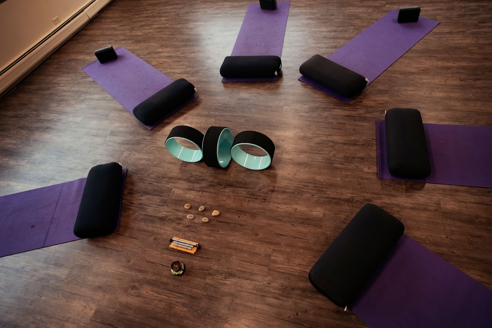 Interior fitness room with purple yoga mats, exercise equipment, wooden flooring, and exercise wheels arranged in circle