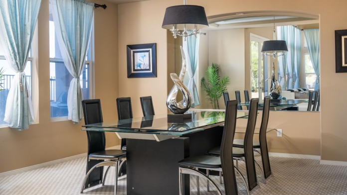 Interior dining room featuring glass top table with black chairs, pendant lighting, and decorative artwork