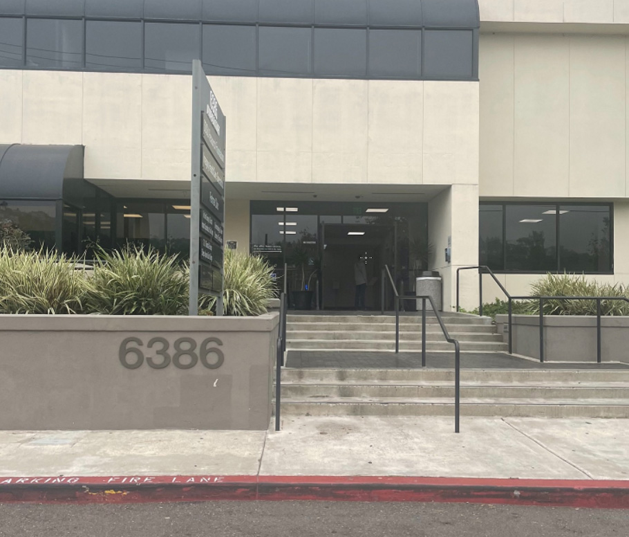 Exterior entrance showing concrete steps, decorative planters, metal railings, glass doors, and building facade number 6386
