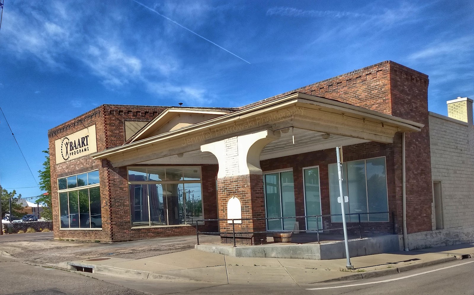 Exterior front facade with brick construction, glass storefront doors, covered entrance canopy, blue sky